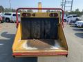 A yellow 2010 Vermeer Corporation BC1200XL wood chipper with a red frame and a wide open chute showing metal blades inside
