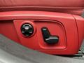 Close-up of a red leather car seat adjustment panel featuring a rotary knob and a lever for seat positioning