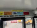 Interior view of a school bus showing signs promoting integrity service and responsibility with an emergency exit door labeled at the bottom