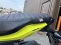 A close-up of a black seat on a yellow 2018 Honda Grom showing the seat's textured surface and the model number 125 on the side
