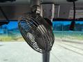 A black metal fan mounted on the dashboard of a 2012 Ford Econoline