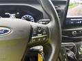 Steering wheel and dashboard controls of a 2023 Ford Transit with a Ford emblem and various buttons for navigation and settings