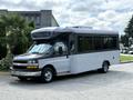A 2020 Chevrolet Express shuttle bus with a sleek design featuring large windows and a high roof showing a combination of black and gray colors