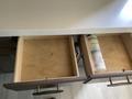 Two empty wooden drawers in a kitchen cabinet of a 2021 Grand Design Recreational ST3478MBS with a bottle of RV degreaser standing upright in one of them