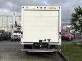 A white 2015 GMC Savana box truck with no visible markings parked with a hitch and step at the rear