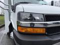 Close-up of a 2013 Chevrolet Express showcasing the front headlight and chrome grille with a visible orange turn signal