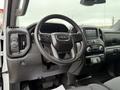 Interior view of a 2022 GMC Sierra 1500 featuring a steering wheel with controls a digital display and dashboard buttons