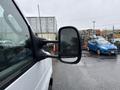 A 2024 Ford E-450 van with a prominent side mirror reflecting rain droplets