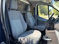 Interior view of a 2016 Ford Transit 150 showing two gray cloth front seats and a central console between them