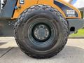 Close-up of a large black tire mounted on a yellow and blue Hyundai HR110C machinery showing detailed tread pattern and rim design