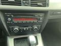 2011 BMW 3-Series dashboard featuring a black audio system with radio display and various control buttons for audio settings