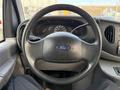 Interior view of a 2002 Ford Econoline featuring a black steering wheel with the Ford logo and gauges visible on the dashboard