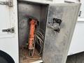 A 2012 Workhorse W62 with an orange jackhammer and coils of wire stored inside a metal compartment