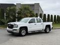 A white 2016 GMC Sierra 1500 pickup truck with chrome accents and a four-door configuration parked on a driveway