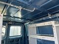 Interior view of a 2005 Ford Econoline showcasing a blue ceiling with metal racks and hooks for storage