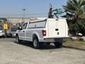 A white 2019 Ford F-150 pickup truck with a high-capacity bed cover parked in a lot