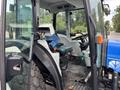 2009 New Holland T4020 tractor with a blue exterior and a spacious operator's cabin featuring a green seat and various control levers and panels