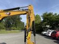 A yellow 2022 Caterpillar 306 excavator arm featuring hydraulic pipes and controls, designed for digging and construction tasks