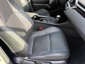 A black leather seat of a 2021 Toyota C-HR with textured fabric on the side and a gear shift in the center console