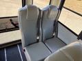 Two gray upholstered seats with seatbelts inside a bus, positioned side by side and attached to the floor
