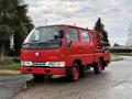 A red 2001 Toyota Dyna truck with a flatbed and hydraulic equipment mounted on the back