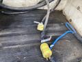 A close-up view of electrical cords including a yellow plug and a blue wire on a textured surface