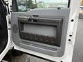 The image shows the interior door panel of a 2012 Ford F-550 featuring a grey plastic design and storage compartment with handle
