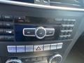 Dashboard controls of a 2013 Mercedes-Benz C-Class featuring audio and climate control buttons and a central dial