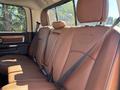 The interior of a 2015 RAM 1500 showcasing brown leather rear seats with seat belts attached