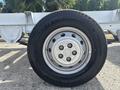 A close-up of a wheel from a 2023 RAM Promaster 3500 with a silver rim and a black tire featuring tread patterns