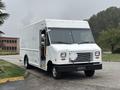 A white 2012 Ford E-450 Super Duty delivery truck with a boxy design and large front windows, parked with the driver's side facing forward