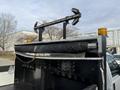 A black 2015 Ford F-350 truck bed with a roll-up cover and an illuminated safety bar mounted at the rear