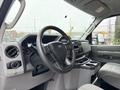 Interior of a 2024 Ford E-450 showing the steering wheel dashboard and control panel with storage compartments and a seating area