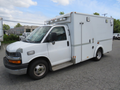A 2011 Chevrolet Express cargo van with a white body and a raised roof featuring side windows and a rear access door