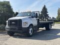 A 2018 Ford F-750 flatbed truck with a white cab and black grille parked on a driveway