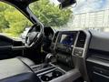 Interior view of a 2019 Ford F-150 featuring a black leather steering wheel dashboard and center console with various controls and a touchscreen display