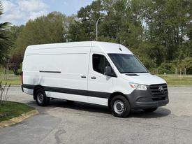 A white 2023 Mercedes-Benz Sprinter van with a sleek design and black accents parked at an angle