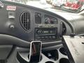 Interior dashboard of a 2006 Ford Econoline featuring climate controls radio display and a smartphone resting in a cup holder