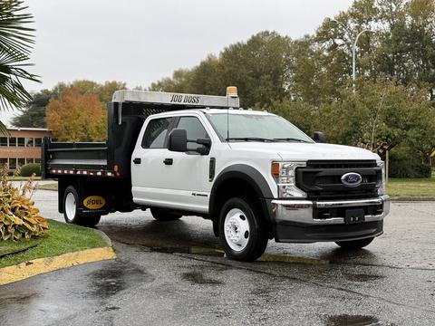 A 2022 Ford F-550 truck with a flatbed and a "Job Boss" truck bed mounted in the back, painted white with black accents and yellow wheels