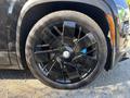 A close-up of a black wheel on a 2023 Fisker Ocean featuring a unique multi-spoke design and a Bridgestone tire