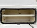 A 2015 Ford F-450 truck with an open storage compartment revealing a white shelf inside