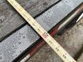 A close-up of a measuring tape placed on a wet wooden surface showing numbers and increments for precise measurement