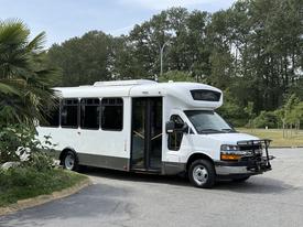 A white 2017 Chevrolet Express with a large passenger door open and a front grill guard parked at an angle
