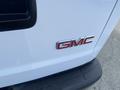 A close-up view of the chrome GMC logo on a white 2022 GMC Savana vehicle