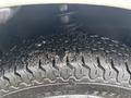 Close-up of a 2010 Suzuki Carry tire featuring a rugged tread pattern and some dirt particles embedded in the grooves