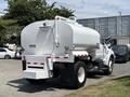 A 2015 Ford F-750 water tanker truck with a large cylindrical white tank and red and white reflective stripes on the rear