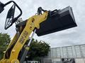 A yellow 2014 Wacker Neuson WL34 wheeled loader with a raised front bucket and a side mirror visible