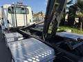 A 2017 International 4300 truck with a flatbed and a visible hydraulic arm system for unloading cargo