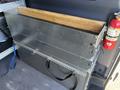 A 2024 Mercedes-Benz Sprinter 2500 with a metallic storage unit featuring multiple sliding drawers and a wooden plank resting on top
