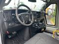 Interior of a 2018 Chevrolet Express featuring a steering wheel dashboard radio controls and a central console with buttons and gear shift
